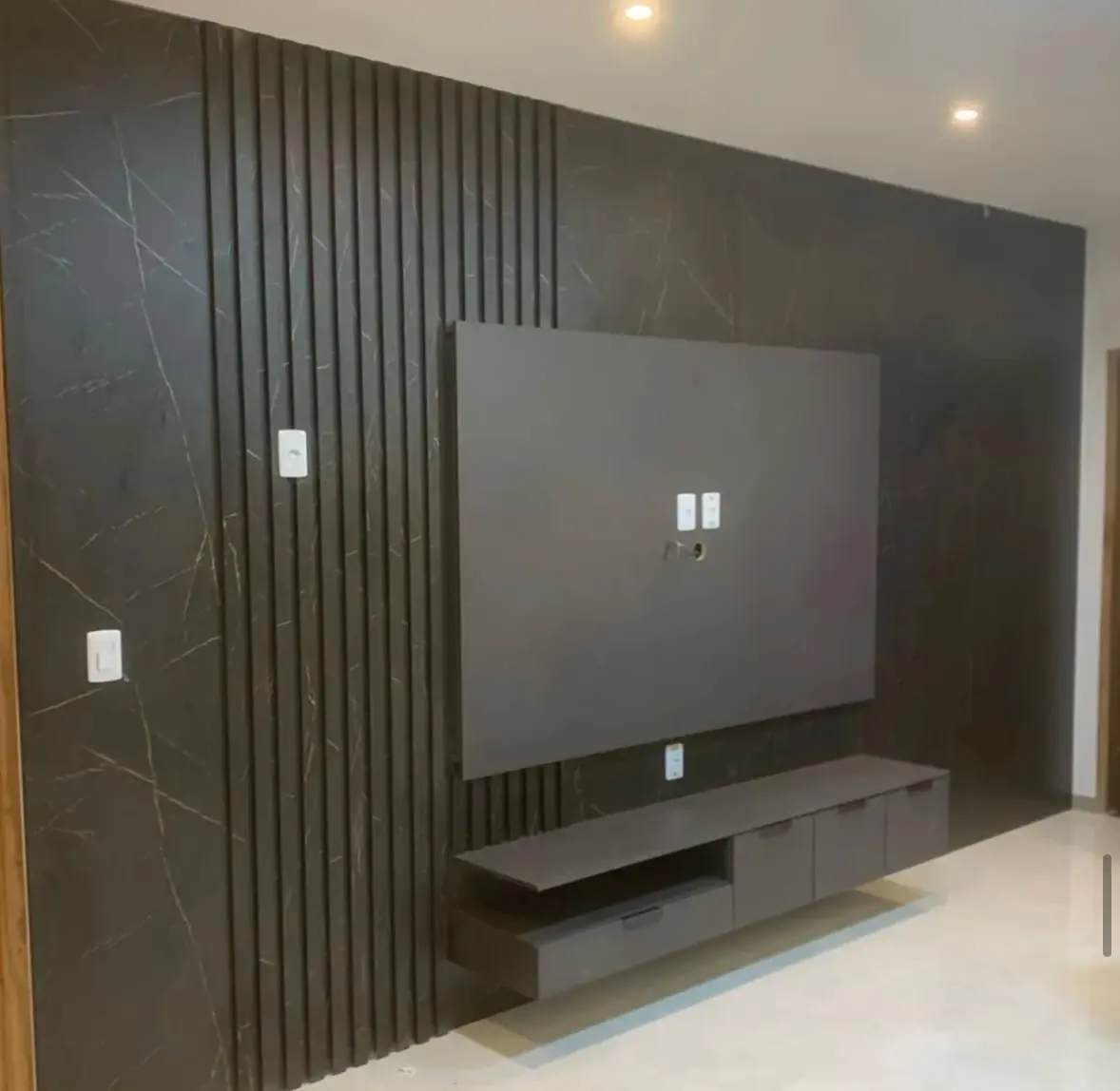 Mármore preto & ripado — Parede em mármore preto com faixa ripada vertical, painel de fundo recuado e rack flutuante em dois níveis.